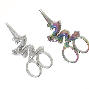 May include: Two pairs of decorative scissors with dragon handles. One pair is silver and the other is iridescent.
