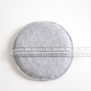 Op de afbeelding: Een grijze viltcirkel met een diameter van ongeveer 28 cm. Een liniaal is over de cirkel gelegd om de grootte te laten zien.