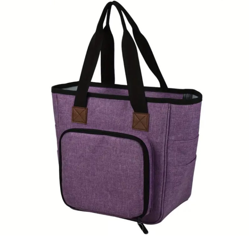 May include: A purple tote bag with black handles and a zippered front pocket. The bag has a brown leather accent on the handles.
