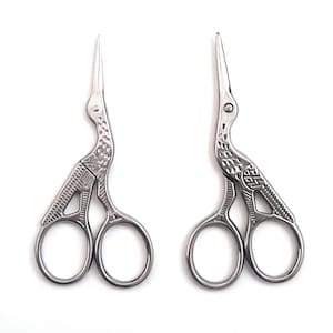 May include: A pair of silver-toned scissors with a bird design. The scissors have a detailed design and are closed.