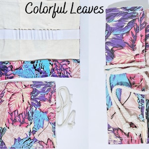 May include: A colorful pencil case with a floral pattern featuring pink, blue, and purple leaves. The case is made of canvas and has a white drawstring closure. The text "Colorful Leaves" is printed on the case.