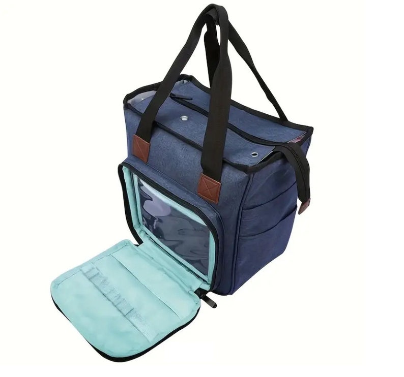 May include: A blue canvas tote bag with a clear plastic window and a zippered pocket. The bag has two black handles and a brown leather accent.
