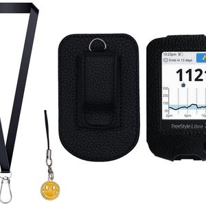 May include: A black leather case and a black lanyard with a silver clasp. A yellow smiley face charm hangs from a black cord. A FreeStyle Libre 3 device displays a glucose reading of 112 mg/dL.