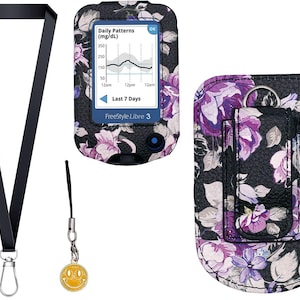 Könnte beinhalten: Ein schwarzes Schlüsselband mit silbernem Clip, ein kleiner gelber Smiley-Anhänger und eine Schutzhülle für ein FreeStyle Libre 3 Glukosemessgerät mit violett-weißem Blumenmuster auf schwarzem Grund, von vorne und hinten gezeigt.