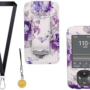 以下が含まれることがあります： 黒いストラップ、シルバーの留め金、黄色のスマイリーフェイスチャーム、紫とグレーの花柄の白いケース。ケースには、血糖値110mg/dLを表示するデバイスが入っています。