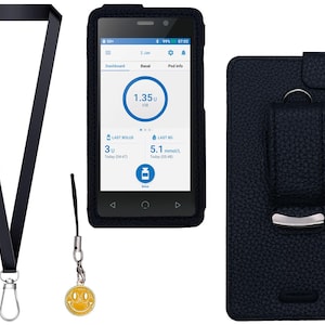 May include: A black lanyard with a silver metal clip, a small yellow smiley face charm on a black cord, and a black textured case containing a digital device with a screen displaying a dashboard with the text 1.35U, 3U, and 5.1 mmol/L.