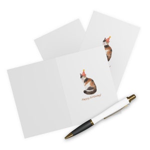 Puede incluir: Una tarjeta de cumplea&ntilde;os con un gato calico que lleva un gorro de fiesta rojo y amarillo. La tarjeta dice "&iexcl;Feliz cumplea&ntilde;os!"