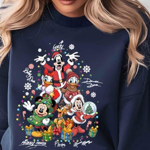 May include: Navy blue sweatshirt featuring a festive design with Disney characters dressed for Christmas. The graphic includes Mickey Mouse, Donald Duck, Goofy, and others, surrounded by snowflakes and gifts. Signatures are also visible.