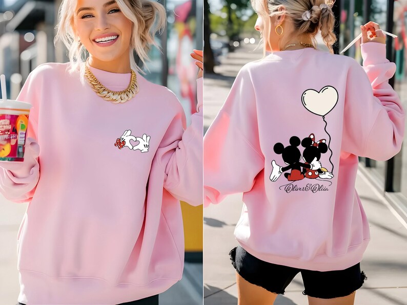 May include: A light pink sweatshirt featuring a white rabbit design with a heart on the front. The back of the sweatshirt has a Mickey and Minnie Mouse graphic with a heart-shaped balloon. The text "Oliver & Olivia" is below the characters.