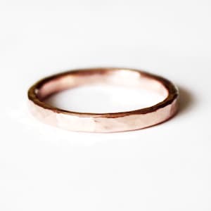 Pode incluir: Uma aliança simples de ouro rosa martelada.