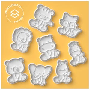 May include: Set of 8 white plastic cookie cutters shaped like various animals, including a lion, zebra, hippopotamus, elephant, tiger, and raccoon. The cutters are on a yellow background with the text "Print & Crafts Factory" in a circle.