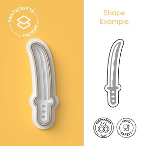 Pode incluir: Cortador de biscoitos em forma de katana de plástico branco e dourado. O cortador está em um fundo amarelo com o texto "Shape Example" e o logotipo Print & Crafts Factory. O cortador pode ser lavado na máquina de lavar louça e é seguro para alimentos.