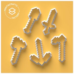 Pode incluir: Cinco cortadores de biscoitos pixelizados brancos em forma de espada, picareta, flecha e martelo sobre um fundo amarelo. O texto "PRINT & CRAFTS FACTORY" está no canto superior esquerdo.