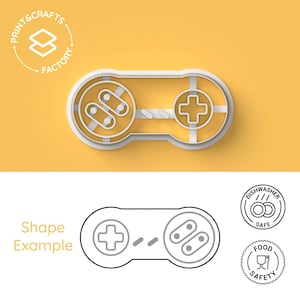Puede incluir: Un cortador de galletas de plástico blanco con forma de mando de videojuego. El cortador de galletas está sobre un fondo amarillo. La imagen también muestra un dibujo en blanco y negro del cortador de galletas, junto con iconos de lavavajillas y seguridad alimentaria.