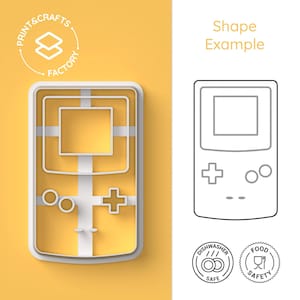 Może przedstawiać: Biała plastikowa foremka do ciasteczek w kształcie przenośnej konsoli do gier wideo. Foremka znajduje się na żółtym tle. Obraz zawiera również rysunek liniowy foremki, dwie ikony wskazujące na zmywarkę i bezpieczeństwo żywności, a także tekst "Przykład kształtu".