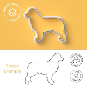 Puede incluir: Un cortador de galletas de plástico blanco con forma de perro pastor australiano. El cortador se muestra sobre un fondo amarillo. Un dibujo de línea del perro se muestra debajo del cortador, junto con iconos de lavavajillas y seguridad alimentaria.