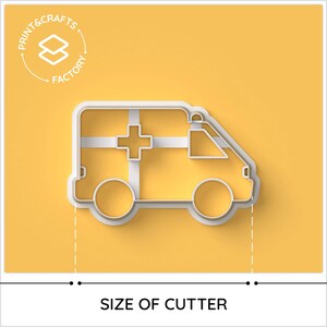 May include: White plastic cookie cutter shaped like an ambulance. The ambulance has a red cross on the side and a white background. The cookie cutter is on a yellow background.