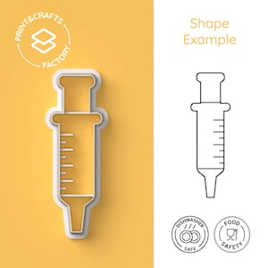 以下が含まれることがあります： 注射器の形をした白いプラスチック製のクッキーカッター。カッターは黄色の背景の上にあります。画像には、注射器の白黒の線画と、食器洗い機対応と食品安全を示す2つの円形のアイコンも含まれています。