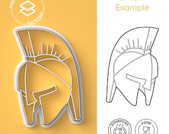 Könnte beinhalten: Ein weißer Plastik-Ausstecher in Form eines spartanischen Helms. Der Ausstecher befindet sich auf einem gelben Hintergrund. Das Bild zeigt auch eine Strichzeichnung des Helms, Spülmaschinen- und Lebensmittelsicherheits-Symbole sowie den Text "Print & Crafts Factory" und "Shape Example".