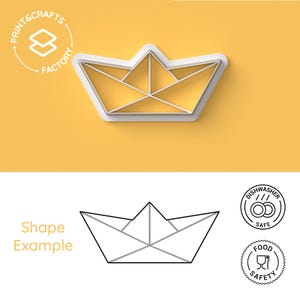 Può includere: Un tagliabiscotti in plastica bianca a forma di barchetta di carta su sfondo giallo. Il tagliabiscotti ha la forma di una barchetta di carta con un design dettagliato. L'immagine include anche un disegno a tratto della barca, le parole "Shape Example" e icone di sicurezza alimentare e lavastoviglie.