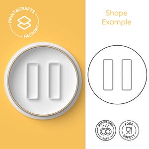 Può includere: Un tagliapasta in ceramica bianca a forma di due rettangoli verticali. Il tagliapasta è su uno sfondo giallo. L'immagine mostra anche un disegno in bianco e nero del tagliapasta, un logo per una fabbrica di stampa e artigianato, e due icone che indicano che il tagliapasta è lavabile in lavastoviglie e sicuro per gli alimenti.