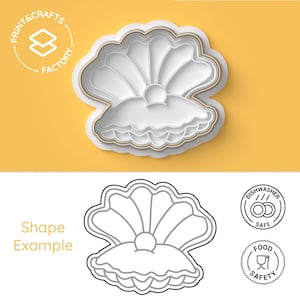 Może przedstawiać: Biała wykrawaczka do ciastek w kształcie muszli z perłą pośrodku. Wykrawaczka ma złoty kontur i znajduje się na żółtym tle. Obraz zawiera również czarno-biały rysunek kształtu muszli oraz ikony wskazujące, że nadaje się do mycia w zmywarce i jest bezpieczny dla żywności.