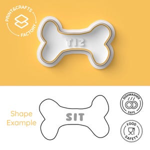 Puede incluir: Cortador de galletas blanco en forma de hueso para perros con la palabra "TIE" en relieve. El cortador tiene un contorno dorado y está sobre un fondo amarillo. La imagen también muestra un dibujo lineal de un cortador de galletas en forma de hueso con la palabra "SIT".