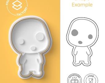 May include: A white cookie cutter in the shape of a cartoon character with large eyes and a surprised expression. The cutter is on a yellow background. The image also shows a black and white outline of the cutter, two icons indicating dishwasher and food safety, and the text "Shape Example".
