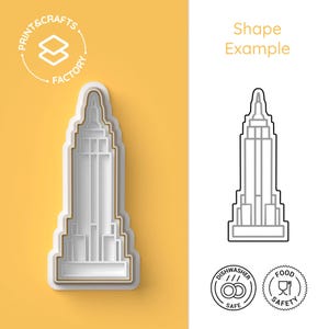 Puede incluir: Cortador de galletas blanco y dorado con forma de Empire State Building con el texto "PRINT & CRAFTS FACTORY". Se muestra un contorno en blanco y negro del edificio junto al cortador. La imagen también incluye iconos de "Apto para lavavajillas" y "Seguridad alimentaria".