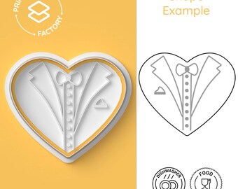 May include: A white heart-shaped cookie cutter with a tuxedo design. The cutter is on a yellow background. The text "Print & Crafts Factory" is in a circle above the cutter. The text "Shape Example" is on the right side of the image. There are two icons below the cutter: one for dishwasher safe and one for food safety.