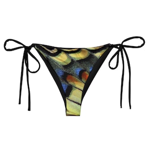 Può includere: Slip bikini nero con fantasia ad ala di farfalla. Il motivo presenta tonalità gialle, blu e arancioni. Lo slip bikini ha lacci neri su ogni lato.