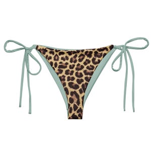 May include: A light blue bikini bottom with a leopard print lining. The bikini bottom has adjustable ties on both sides.