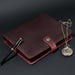 May include: A dark burgundy leather binder featuring a snap closure with a silver-toned floral button. A black fountain pen with gold accents rests on the left side, and a vintage-style gold pocket watch with a chain lies on the right side.