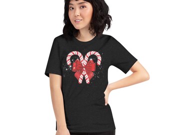 May include: Dark gray t-shirt featuring a festive design. The graphic showcases two candy canes forming a heart shape, with a red bow in the center. The candy canes are red and white striped. The design is sprinkled with white dots.