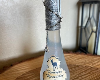 May include: A decorative glass bottle with a silver-wrapped neck and a white wax seal. The bottle has a label that reads "Pensieve Memories" with a deer silhouette and the text "Severus Snape 1998". A silver chain and charm hang from the neck.