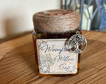 May include: A small glass jar with a brown label that reads "Womping Willow Sap". The jar is tied with twine and has a charm attached to it in the shape of a tree.