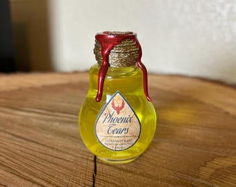 May include: A small glass bottle with a gold lid and red wax seal. The bottle is filled with a yellow liquid and has a label that reads "Phoenix Tears Extremely Rare Immune System Healing Powers".