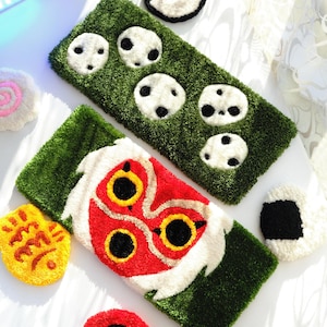Two anime tufted keyboard rugs – Mononoke and Kodama designs – handmade acrylic desk rugs on white table