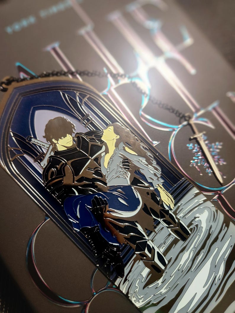 May include: A metal pendant featuring a couple embracing within a gothic arch design. The pendant has a silver finish with blue and black accents. A sword-shaped charm hangs from a chain. The background is dark with iridescent details.
