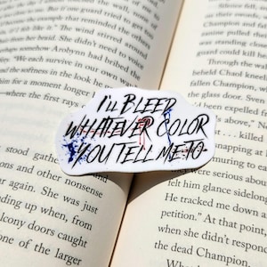 以下が含まれることがあります： I'LL BLEED WHATEVER COLOR YOU TELL ME TOという黒い手書き風の文字が書かれた白いダイカットステッカー。文字の背後には抽象的な青と赤の絵の具の飛沫がデザインされており、大胆な視覚的コントラストを生み出しています。