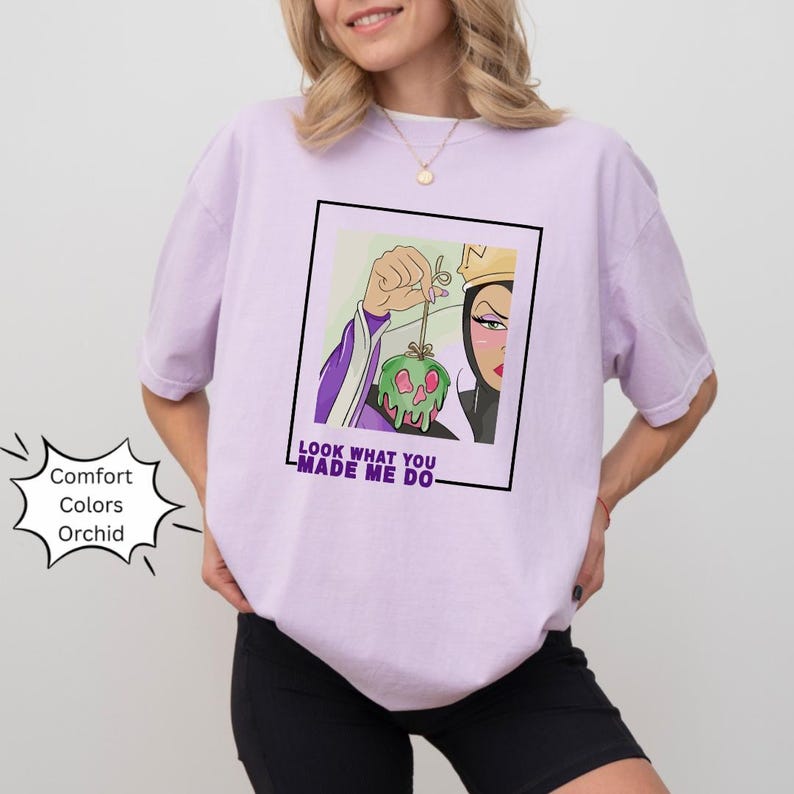 K&ouml;nnte beinhalten: Ein lila T-Shirt mit einem Grafikdruck der b&ouml;sen K&ouml;nigin aus Schneewittchen, die einen vergifteten Apfel h&auml;lt. Der Text "Look what you made me do" ist unter dem Grafikdruck aufgedruckt.
