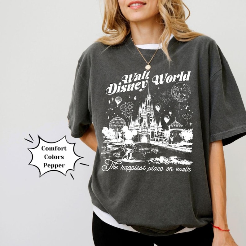 May include: A dark grey t-shirt featuring a white graphic of the Walt Disney World castle and Mickey Mouse. The text "Walt Disney World" and "The happiest place on earth" are also printed on the shirt.