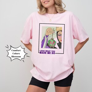 K&ouml;nnte beinhalten: Pinkes T-Shirt mit einem Grafikdruck der b&ouml;sen K&ouml;nigin aus Schneewittchen, die einen vergifteten Apfel h&auml;lt. Der Text "Look what you made me do" ist unter dem Grafikdruck aufgedruckt.