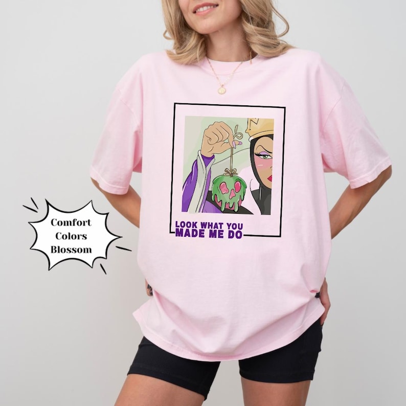 K&ouml;nnte beinhalten: Pinkes T-Shirt mit einem Grafikdruck der b&ouml;sen K&ouml;nigin aus Schneewittchen, die einen vergifteten Apfel h&auml;lt. Der Text "Look what you made me do" ist unter dem Grafikdruck aufgedruckt.