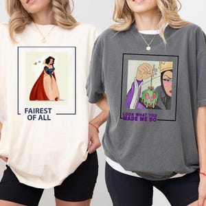 K&ouml;nnte beinhalten: Zwei T-Shirts mit unterschiedlichen Designs, die Figuren aus dem Disney-Film Schneewittchen zeigen. Das erste Shirt ist elfenbeinfarben mit einer Grafik von Schneewittchen in einem roten und blauen Kleid. Der Text "Fairest of All" ist unter der Grafik gedruckt. Das zweite Shirt ist grau mit einer Grafik der b&ouml;sen K&ouml;nigin, die einen vergifteten Apfel h&auml;lt. Der Text "Look what you made me do" ist unter der Grafik gedruckt.