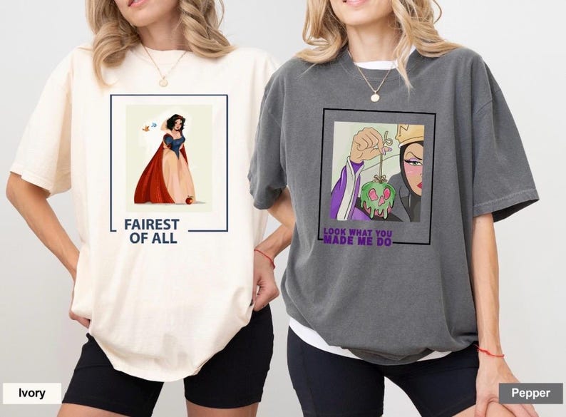 K&ouml;nnte beinhalten: Zwei T-Shirts mit unterschiedlichen Designs, die Figuren aus dem Disney-Film Schneewittchen zeigen. Das erste Shirt ist elfenbeinfarben mit einer Grafik von Schneewittchen in einem roten und blauen Kleid. Der Text "Fairest of All" ist unter der Grafik gedruckt. Das zweite Shirt ist grau mit einer Grafik der b&ouml;sen K&ouml;nigin, die einen vergifteten Apfel h&auml;lt. Der Text "Look what you made me do" ist unter der Grafik gedruckt.