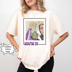 K&ouml;nnte beinhalten: Ein wei&szlig;es T-Shirt mit einem Grafikdruck der b&ouml;sen K&ouml;nigin aus Schneewittchen, die einen vergifteten Apfel h&auml;lt. Der Text "Look what you made me do" ist unter dem Grafikdruck aufgedruckt.