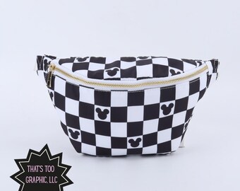 May include: A black and white checkered fanny pack featuring small black mouse ear silhouettes within select squares. The bag has a gold-toned zipper closure across the top. A black starburst-shaped logo in the corner displays the text THAT'S TOO GRAPHIC, LLC.