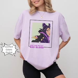 May include: A purple t-shirt with a graphic of Maleficent from Disney's Sleeping Beauty. The graphic includes a quote that says "Baby now we got bad blood".