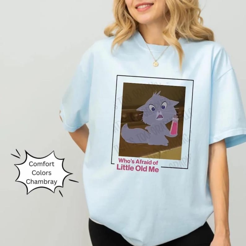 May include: Light blue t-shirt with a cartoon cat image and the text "Who's Afraid of Little Old Me". The shirt is made of a soft, comfortable fabric.